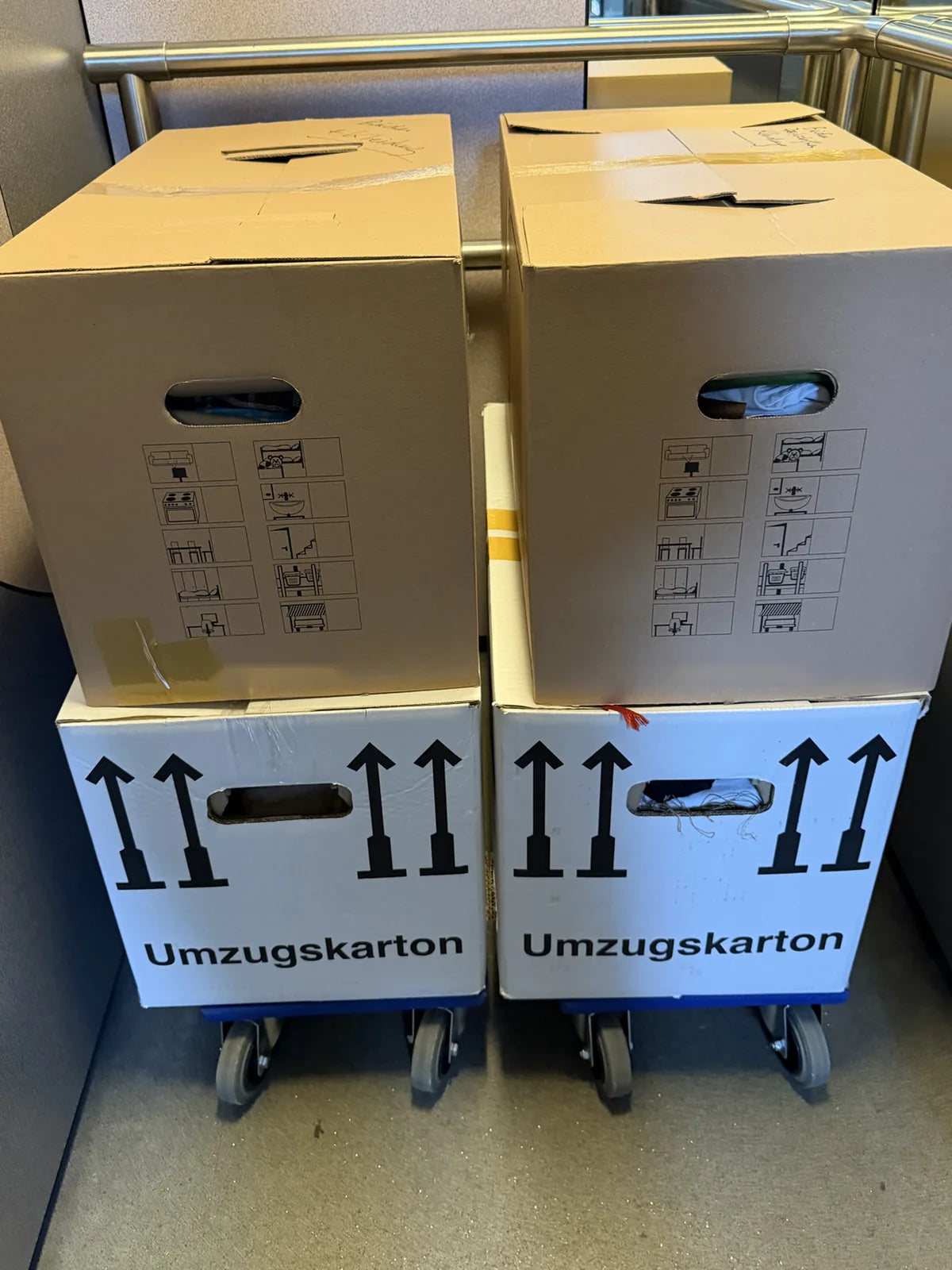 Zwei Möbelroller mit gestapelten Umzugskartons im Lift