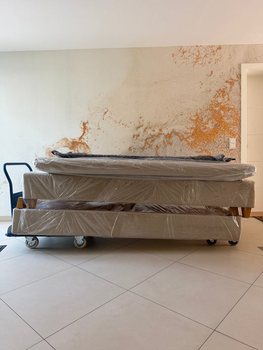 Boxspringbett komplett in Folie verpackt auf Plattformwagen und Möbelroller in der Wohnung transportieren