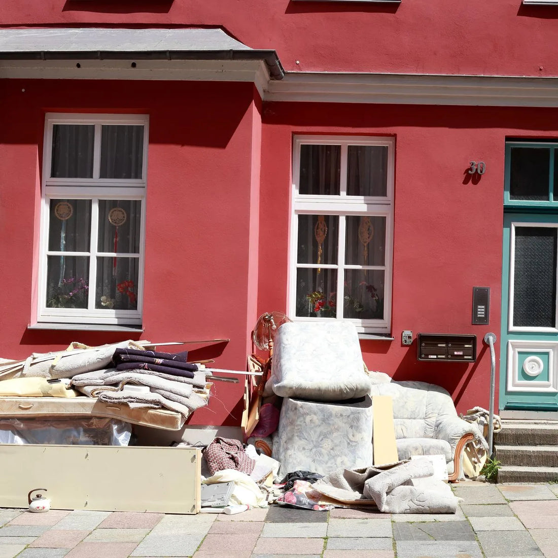 Sperrmüll und alte Möbel vor einer roten Hausfassade nach einer Entrümpelung
