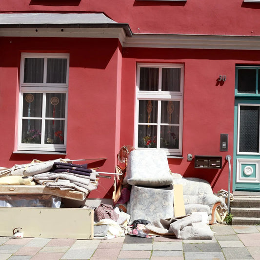 Sperrmüll und alte Möbel vor einer roten Hausfassade nach einer Entrümpelung