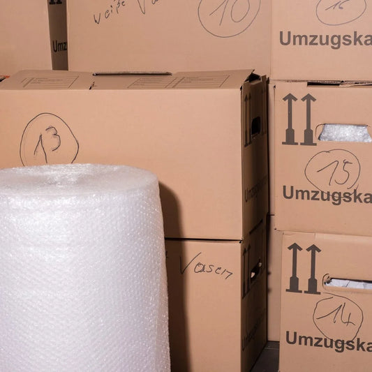 Beschriftete Umzugskartons und eine Rolle Luftpolsterfolie
