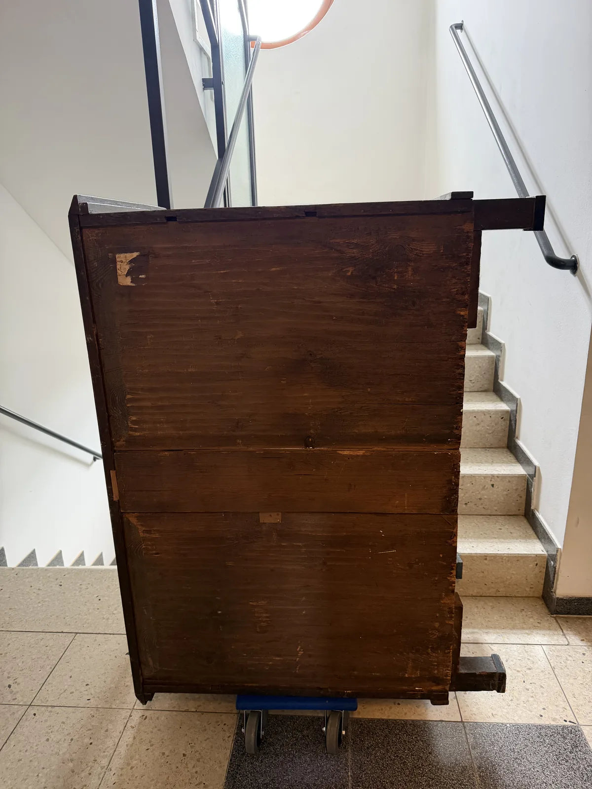 Antiker Holzkasten auf Möbelroller vor der Stiege