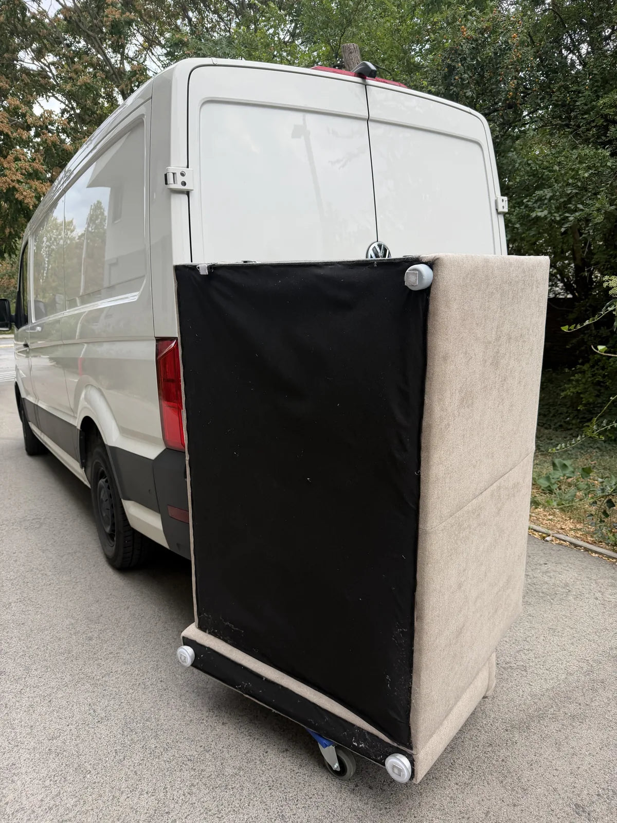 Sofa hochkant auf Möbelroller vor dem Transporter
